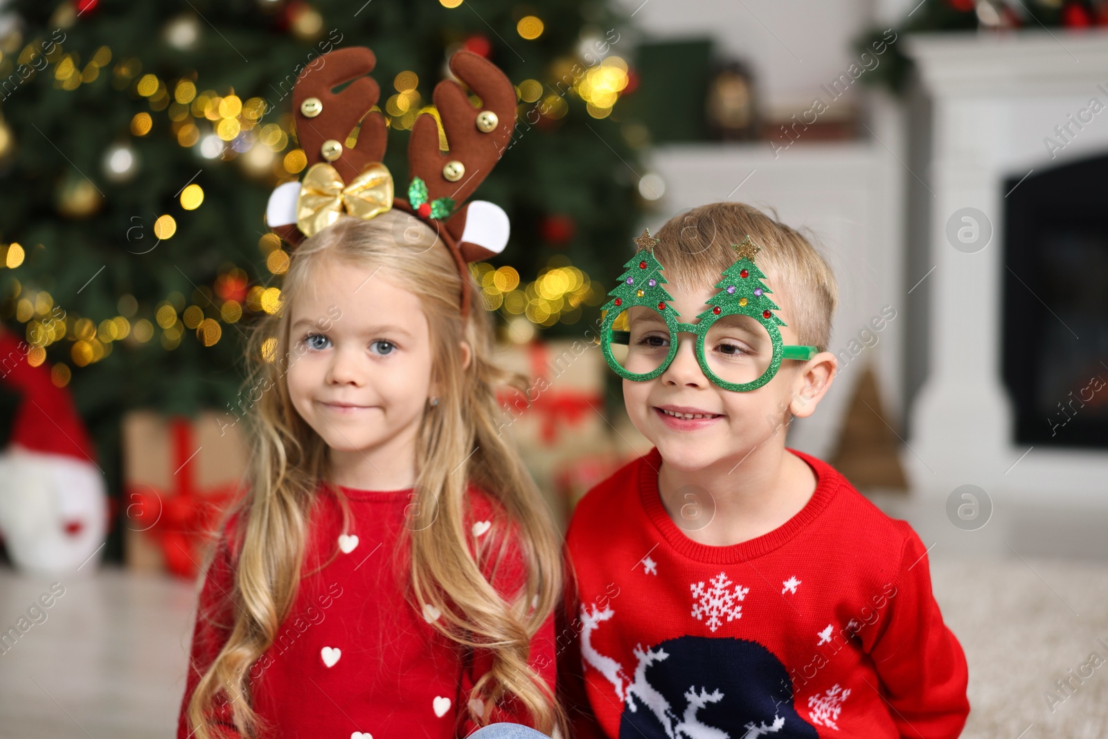 Photo of Cute little children in Christmas sweaters at home