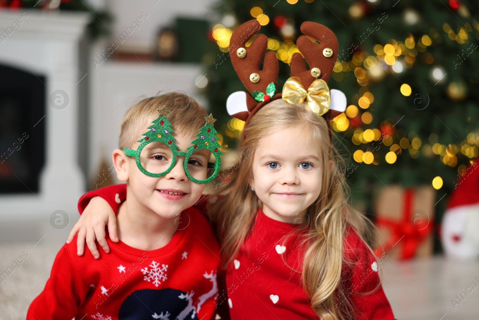 Photo of Cute little children in Christmas sweaters at home