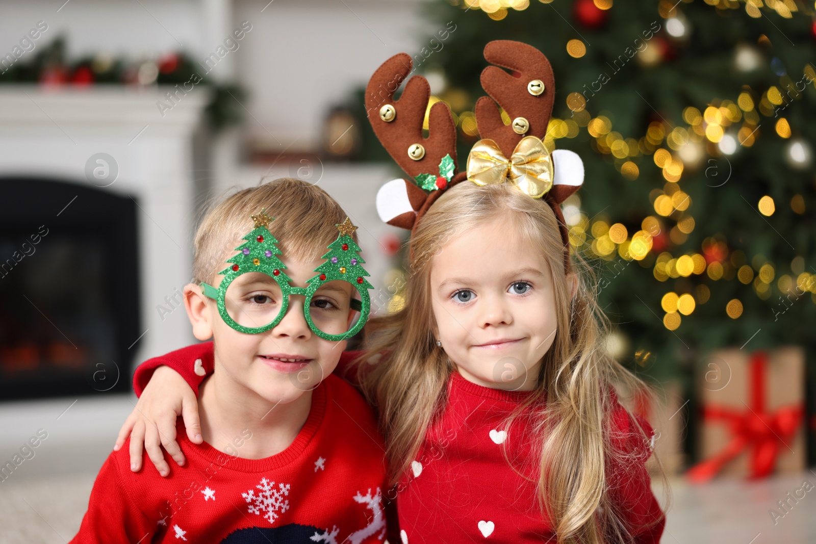 Photo of Cute little children in Christmas sweaters at home