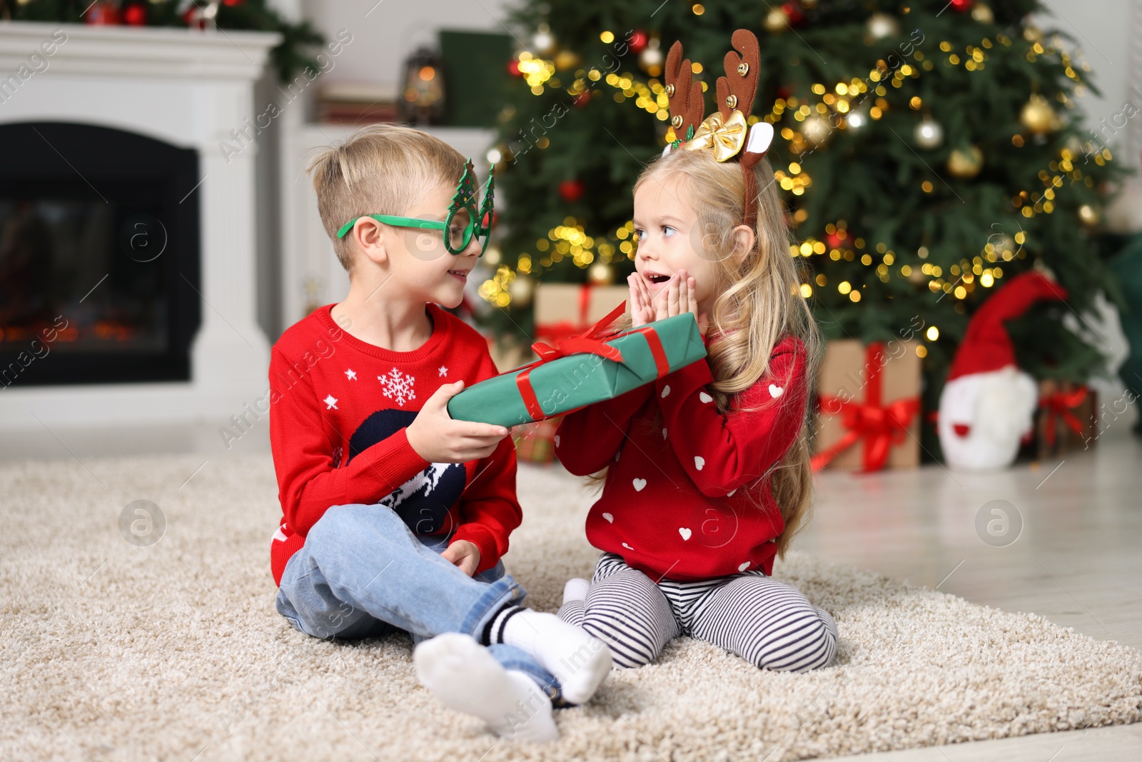 Photo of Little boy giving Christmas gift to girl at home