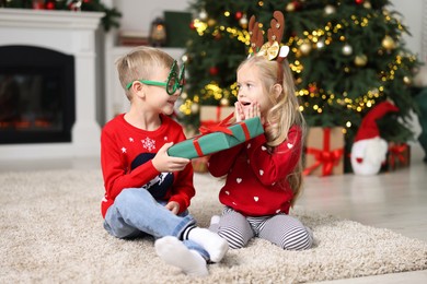 Photo of Little boy giving Christmas gift to girl at home