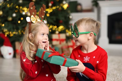 Photo of Little boy giving Christmas gift to girl at home