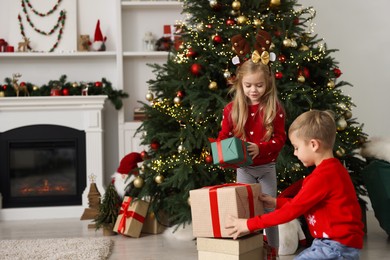 Photo of Little children with gifts near Christmas tree at home. Space for text