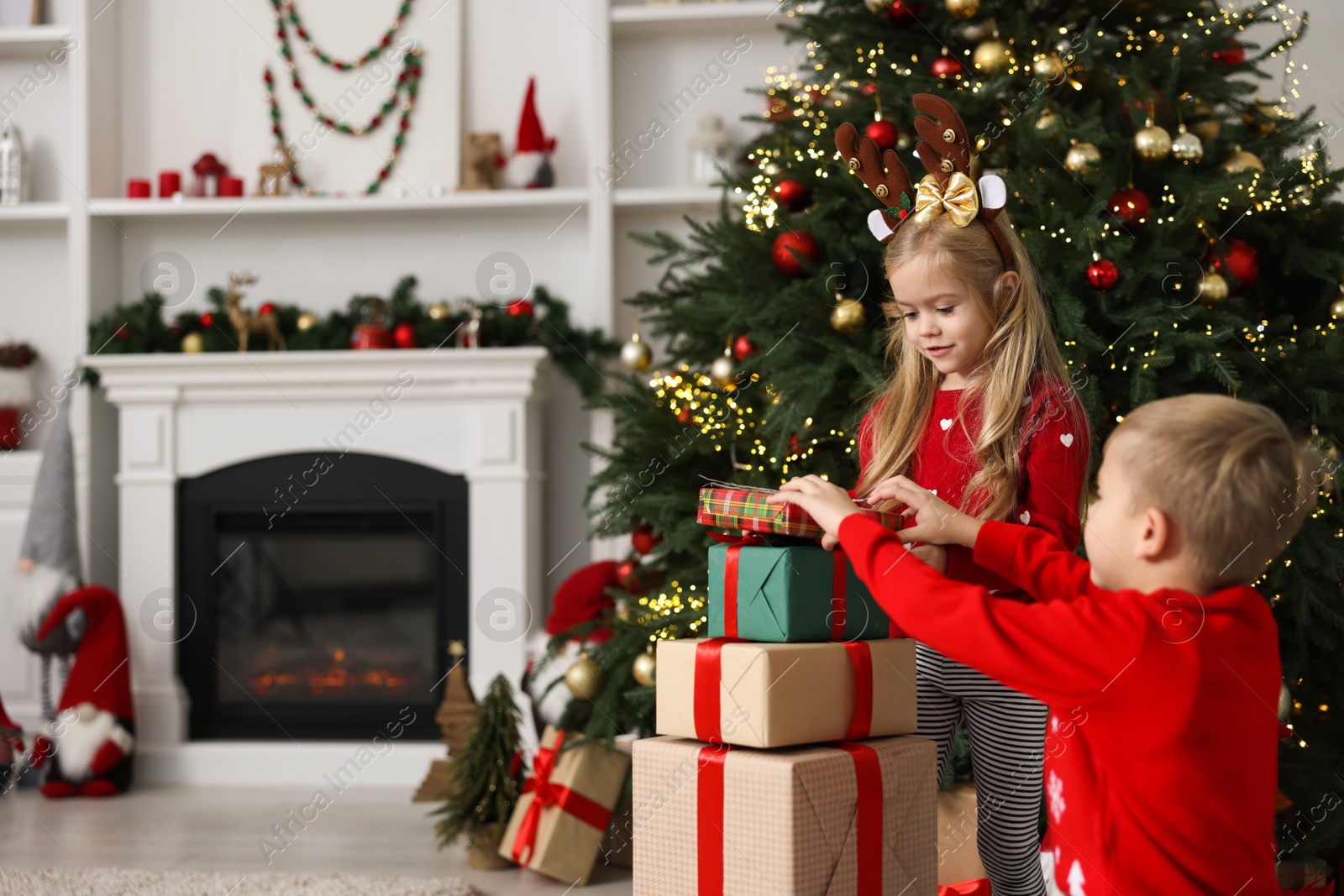 Photo of Little children with gifts near Christmas tree at home. Space for text