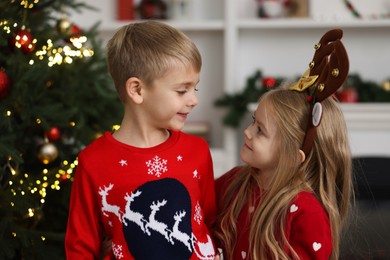 Adorable little kids in Christmas sweaters at home