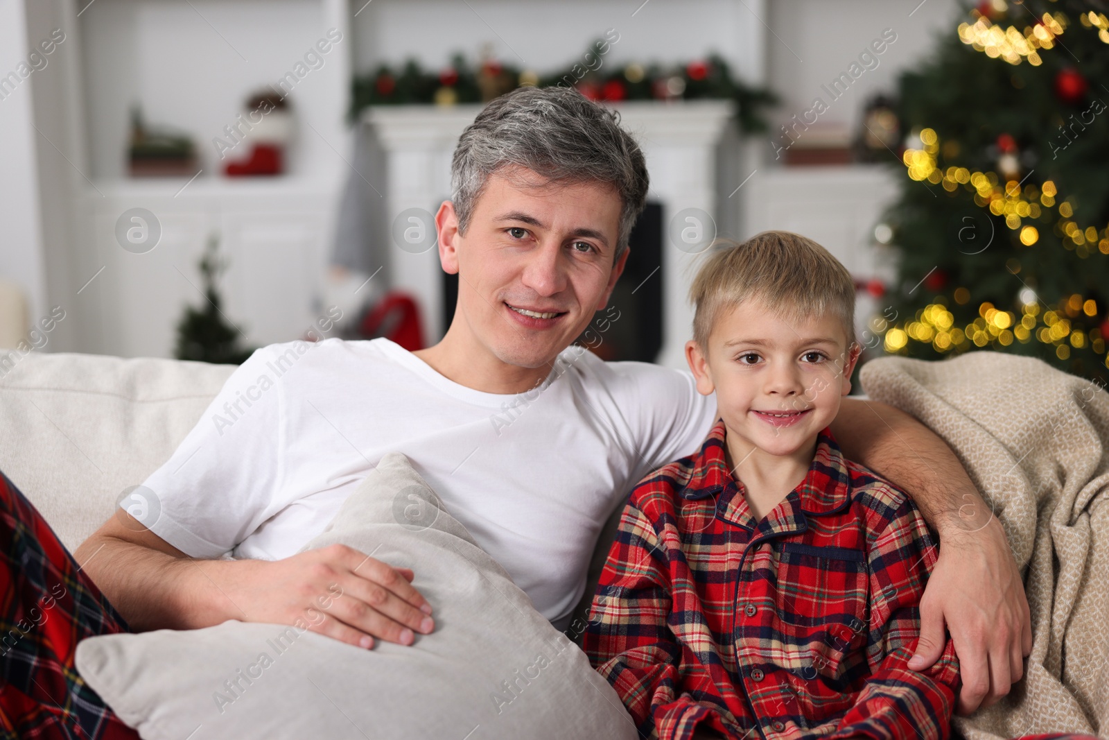 Photo of Father and son in pajamas on sofa at home. Christmas morning