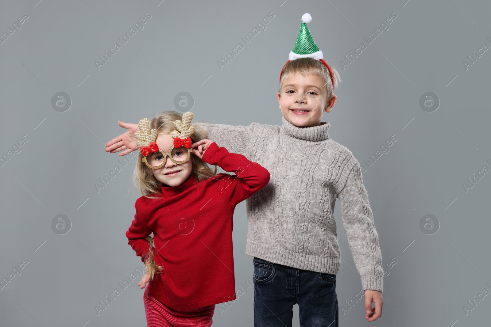 Photo of Funny children in Christmas accessories on grey background