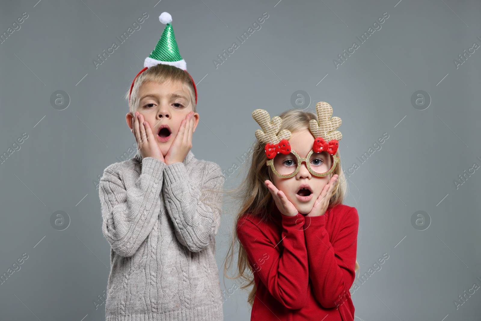 Photo of Funny children in Christmas accessories on grey background