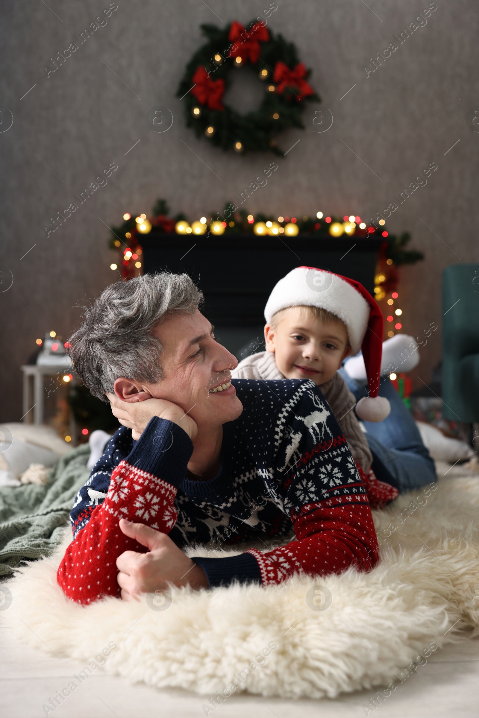 Photo of Dad and son near decorated fireplace at home. Christmas season