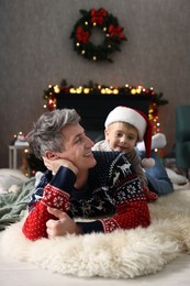 Photo of Dad and son near decorated fireplace at home. Christmas season