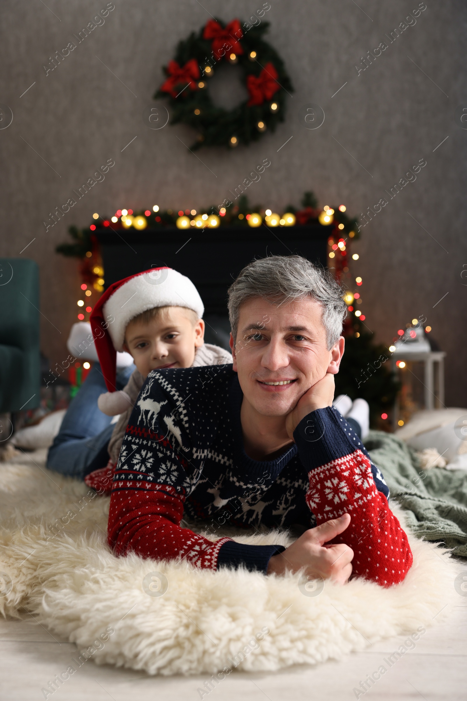 Photo of Dad and son near decorated fireplace at home. Christmas season