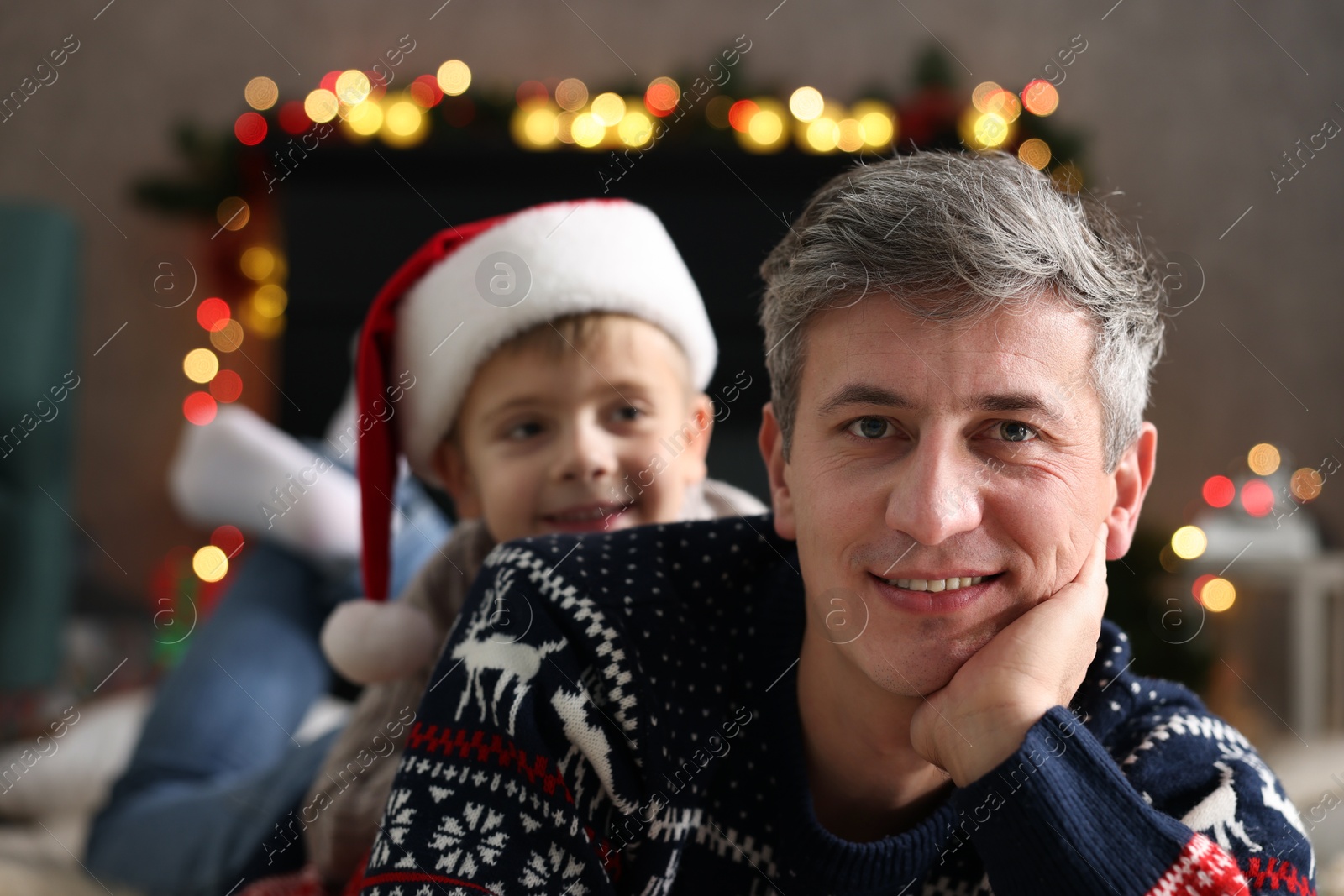 Photo of Dad and son near decorated fireplace at home, selective focus. Christmas season