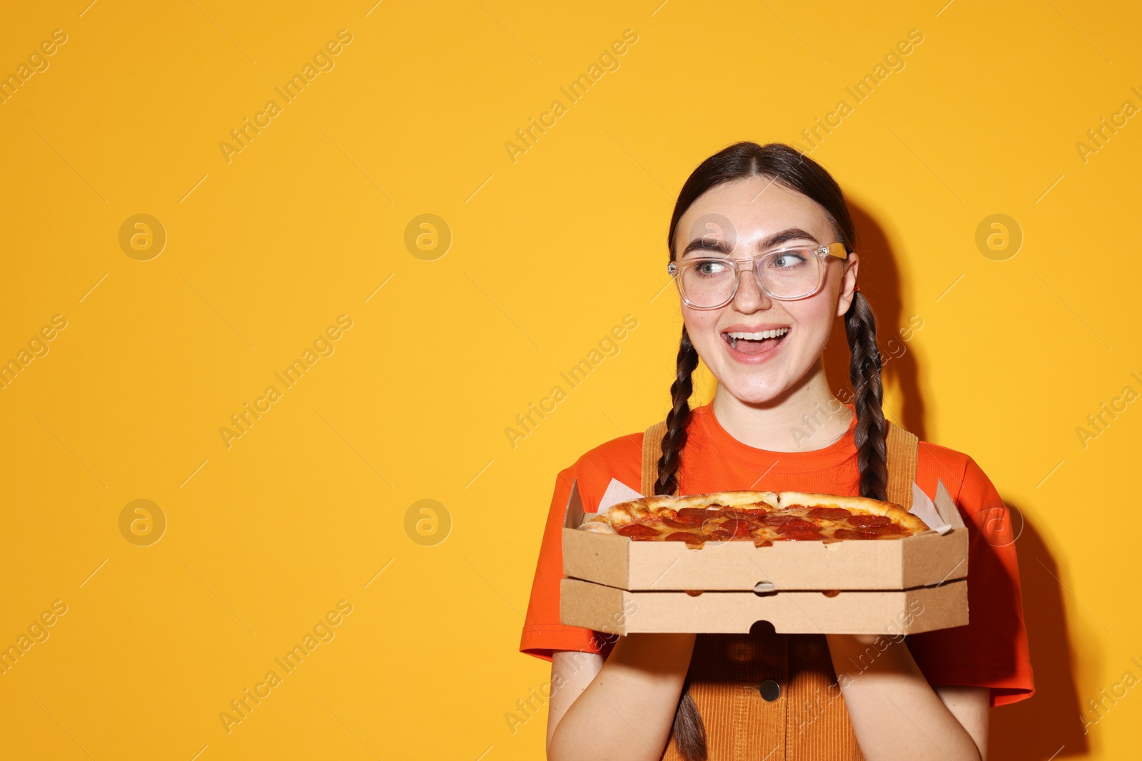 Photo of Beautiful woman with delicious pizza on orange background, space for text