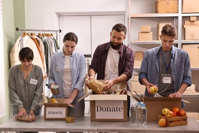 Group of volunteers packing food donations at table indoors