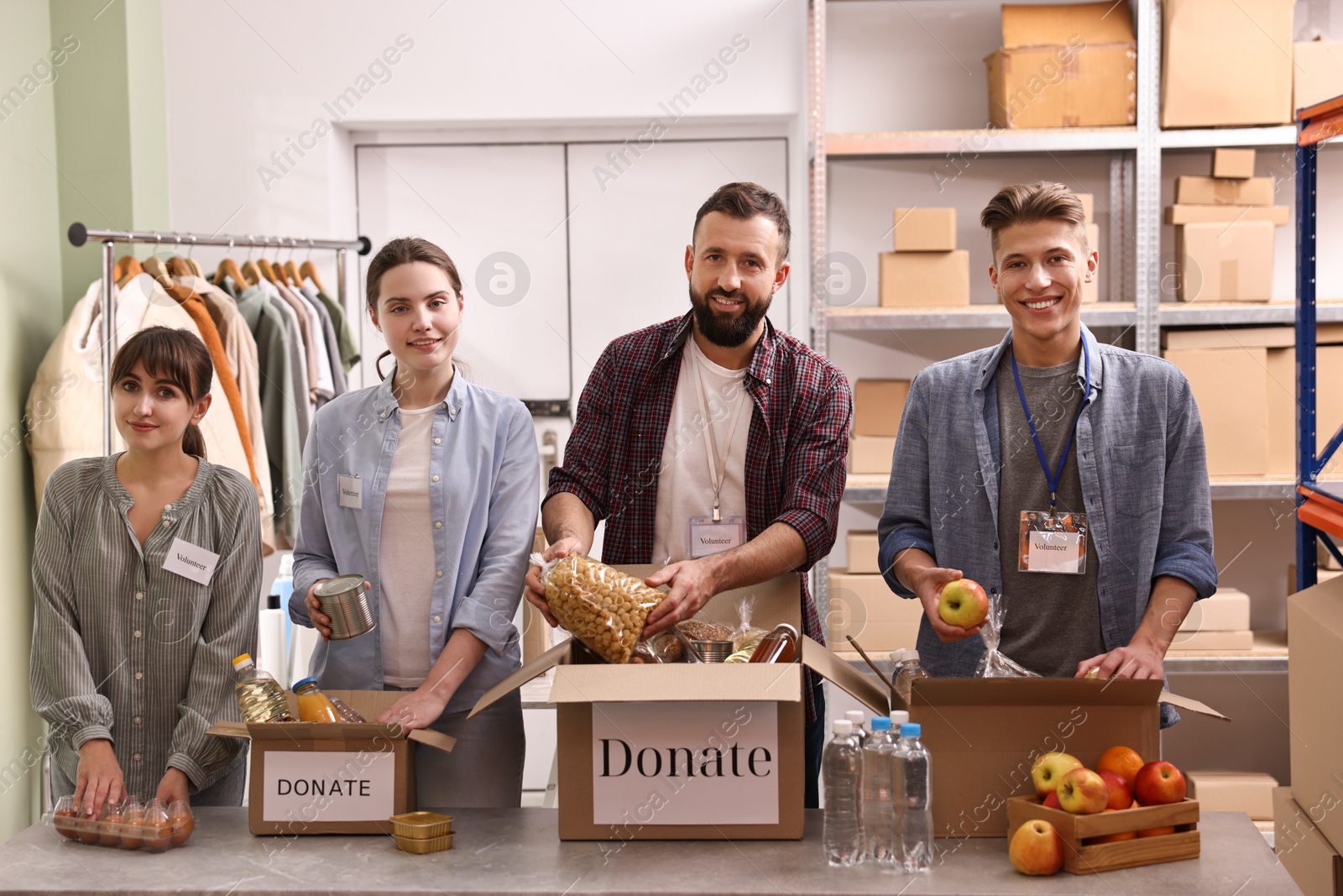 Photo of Group of volunteers packing food donations at table indoors