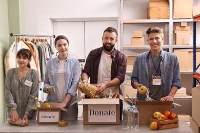 Photo of Group of volunteers packing food donations at table indoors