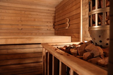 Photo of Wooden sauna with bench, stove and hot stones