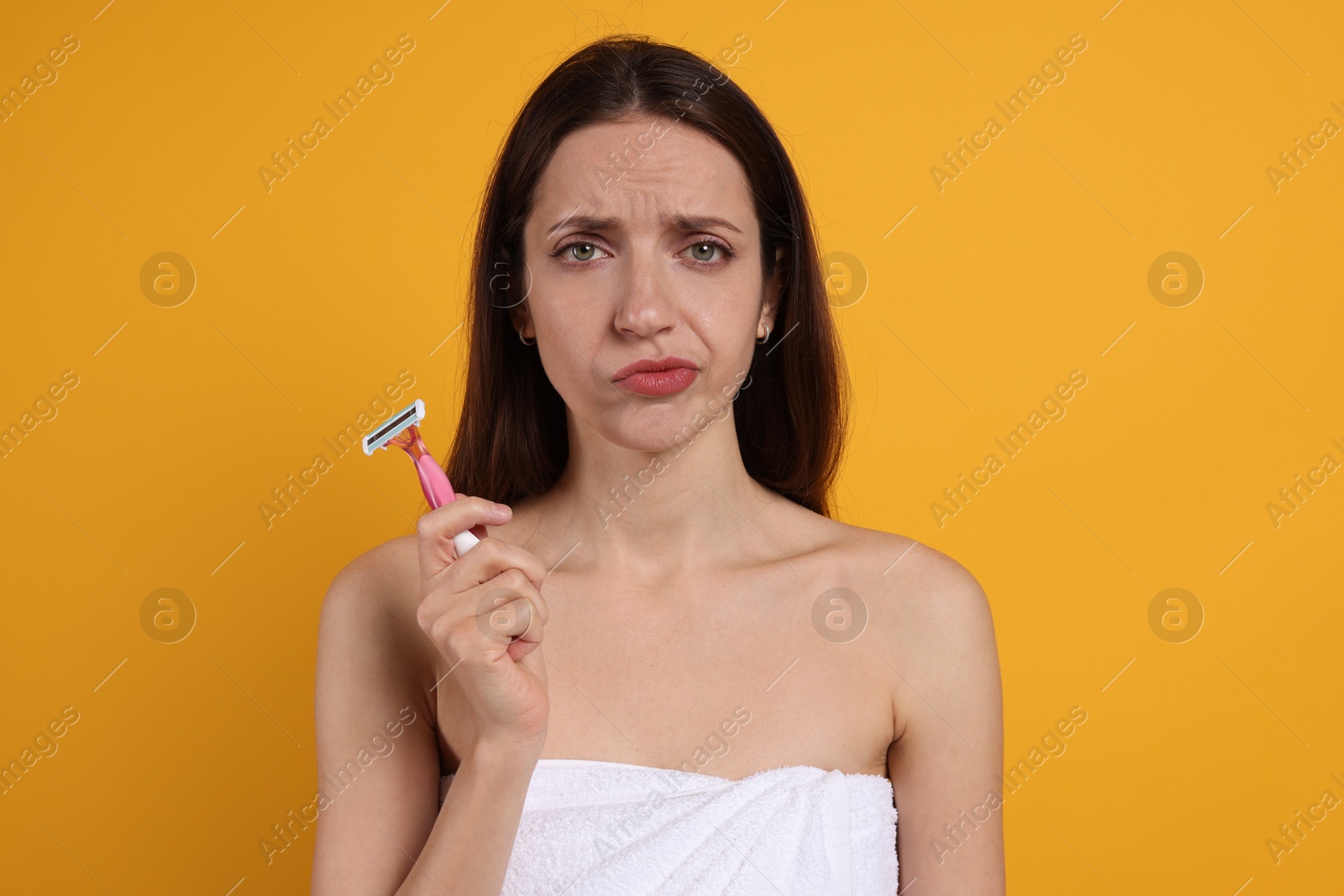 Photo of Woman with razor on orange background. Hair removal tool