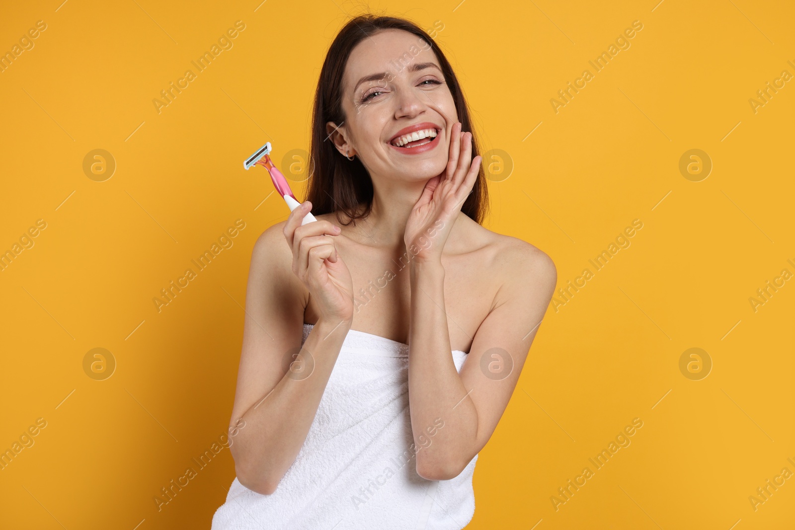 Photo of Happy woman with razor on orange background. Hair removal tool