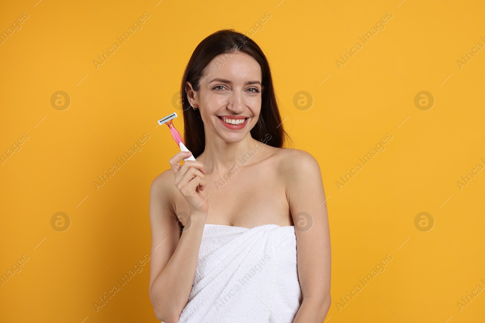 Photo of Happy woman with razor on orange background. Hair removal tool