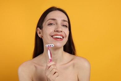 Photo of Happy woman shaving her facial hair with razor on orange background