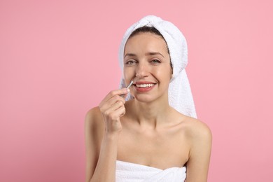 Happy woman plucking her mustache with tweezers on pink background