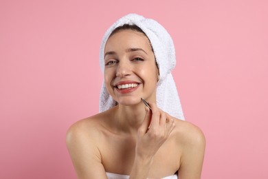 Happy woman plucking her facial hair with tweezers on pink background