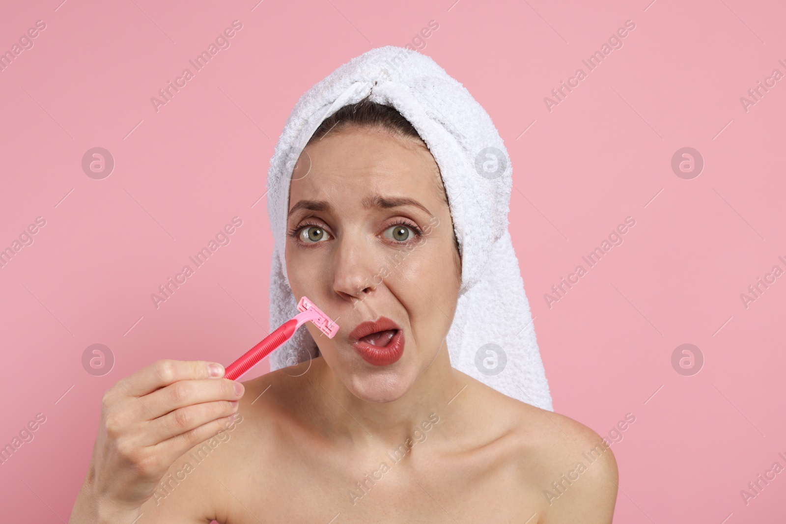 Photo of Beautiful woman shaving her mustache with razor on pink background