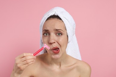 Beautiful woman shaving her mustache with razor on pink background