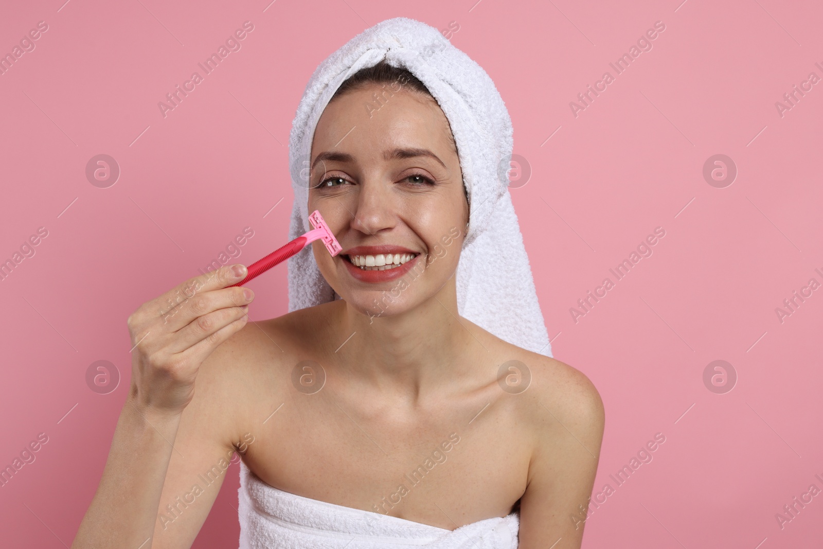 Photo of Happy woman shaving her mustache with razor on pink background