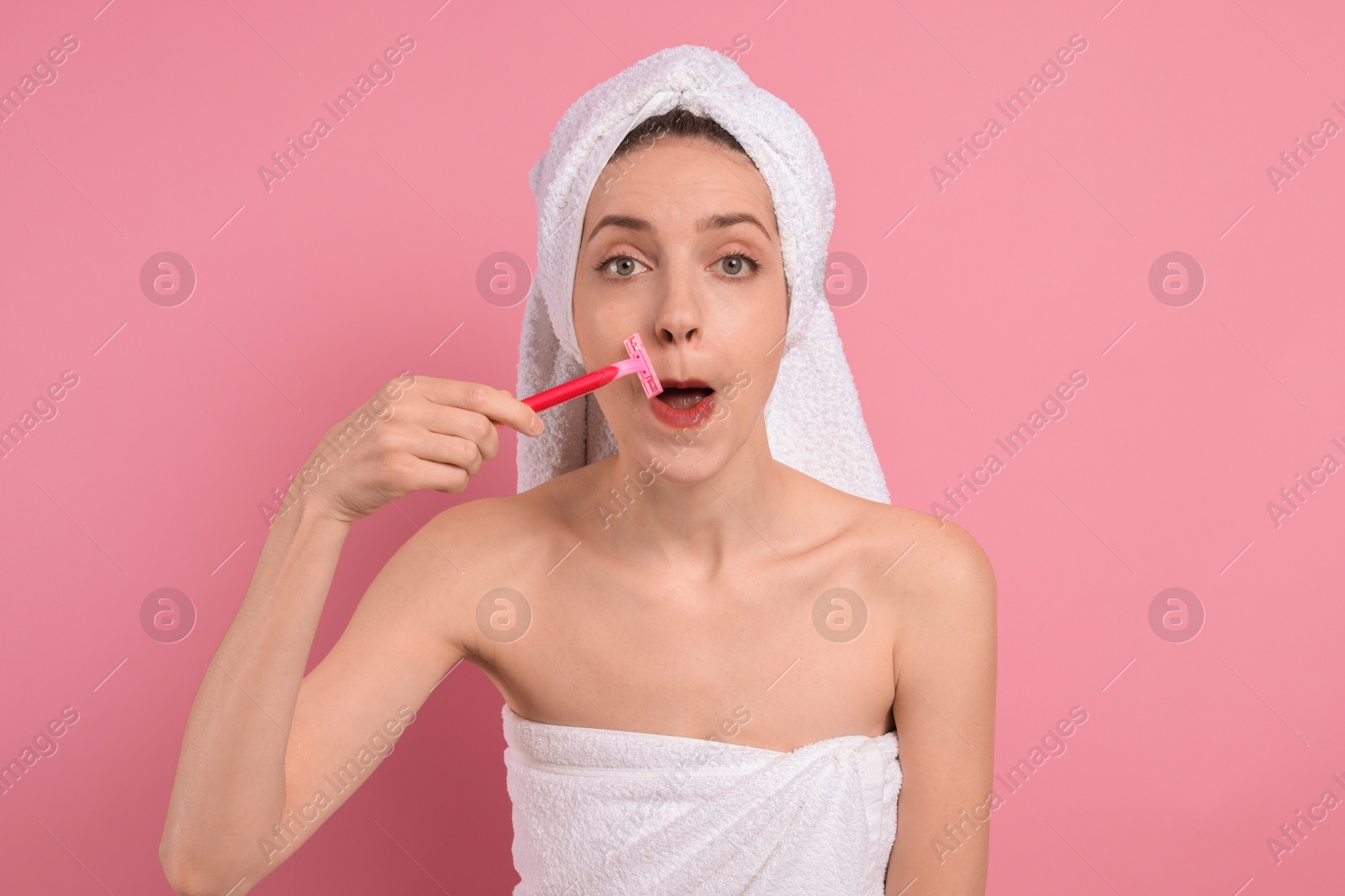 Photo of Beautiful woman shaving her mustache with razor on pink background