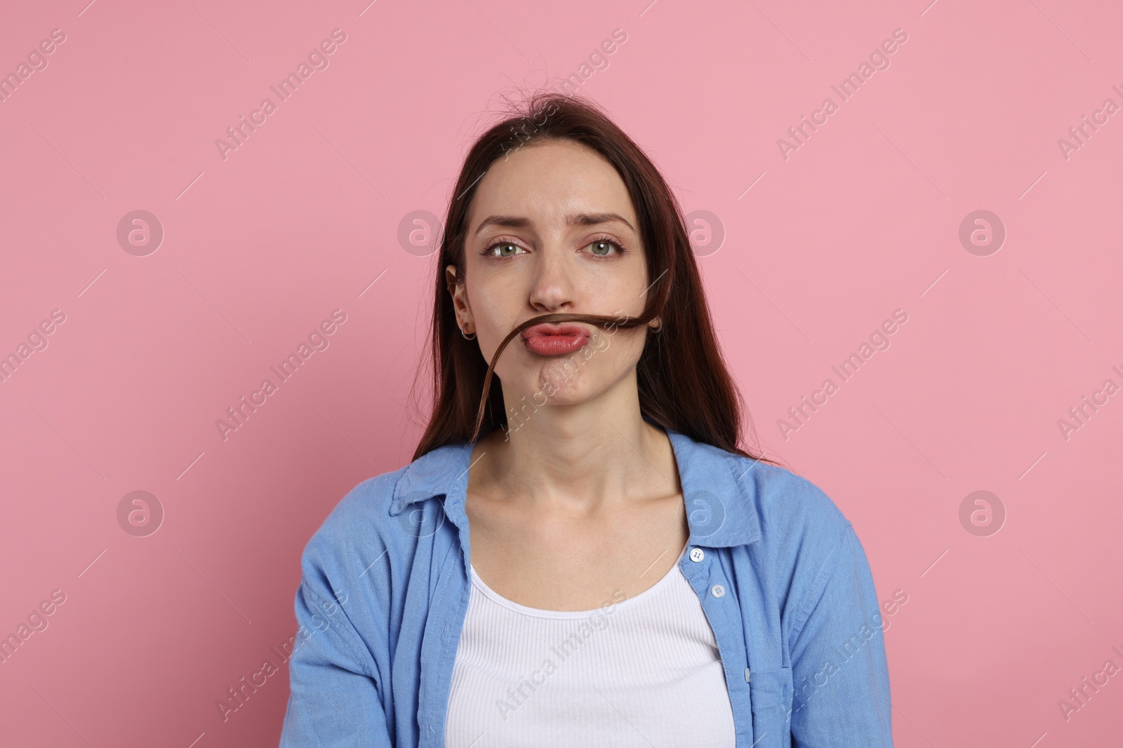 Photo of Funny woman making mustache from her hair on pink background