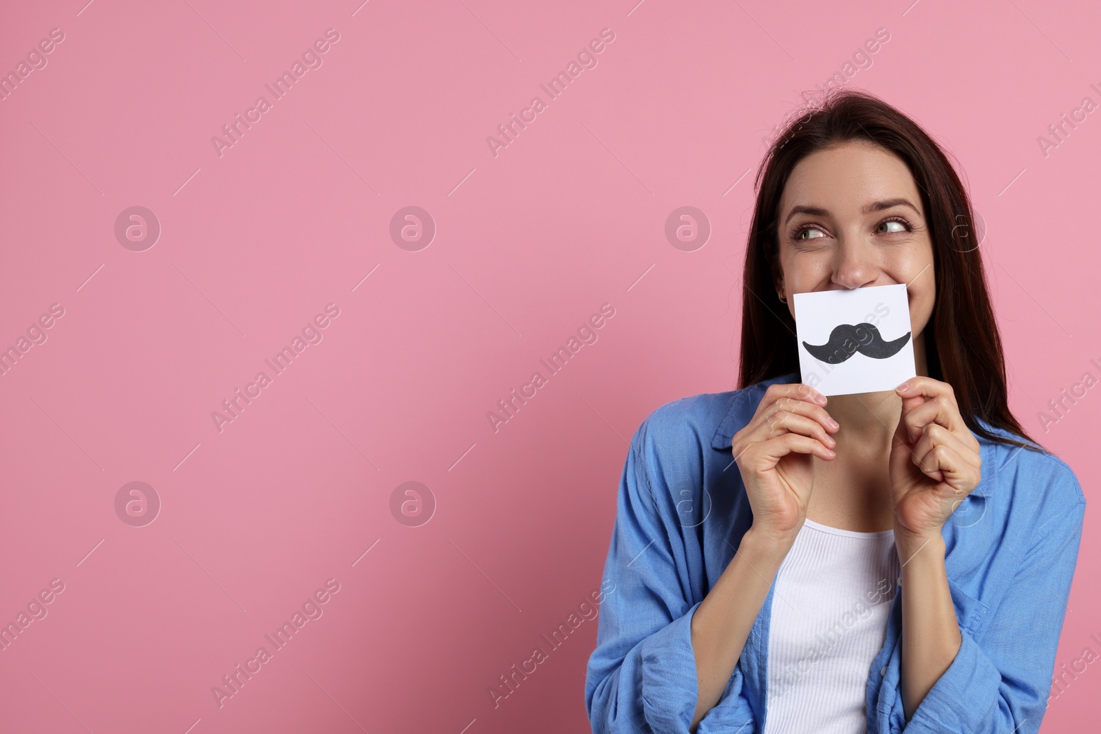 Photo of Woman holding paper with drawn mustache on pink background. Space for text