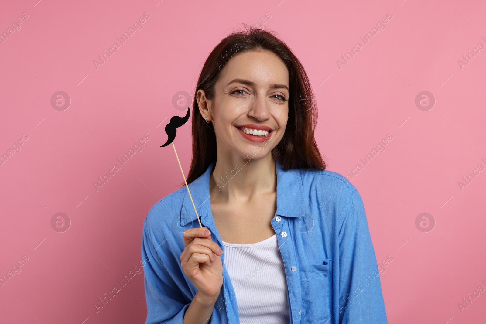 Photo of Happy woman with fake paper mustache on pink background