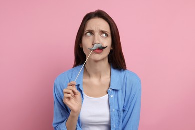 Woman with fake paper mustache on pink background