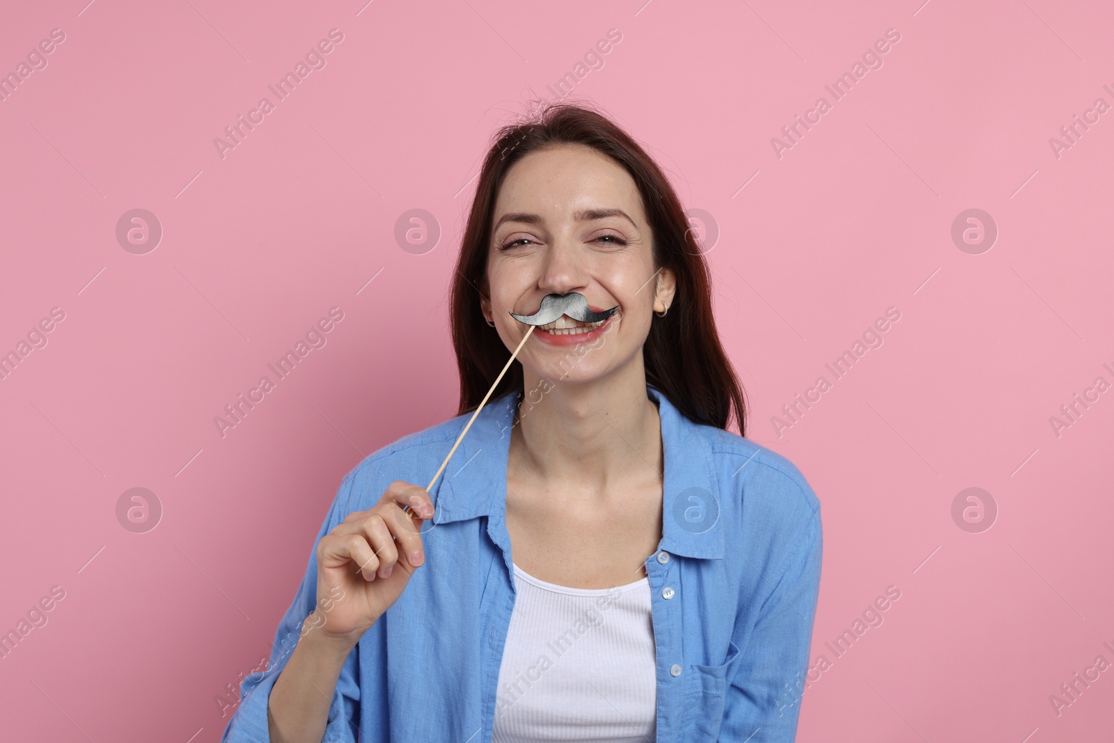 Photo of Happy woman with fake paper mustache on pink background