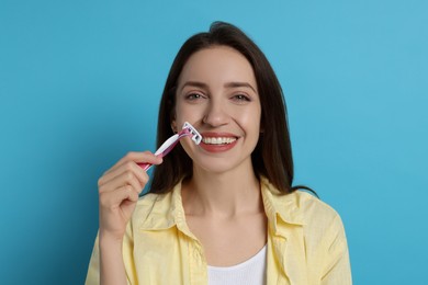 Photo of Happy woman shaving her mustache with razor on light blue background