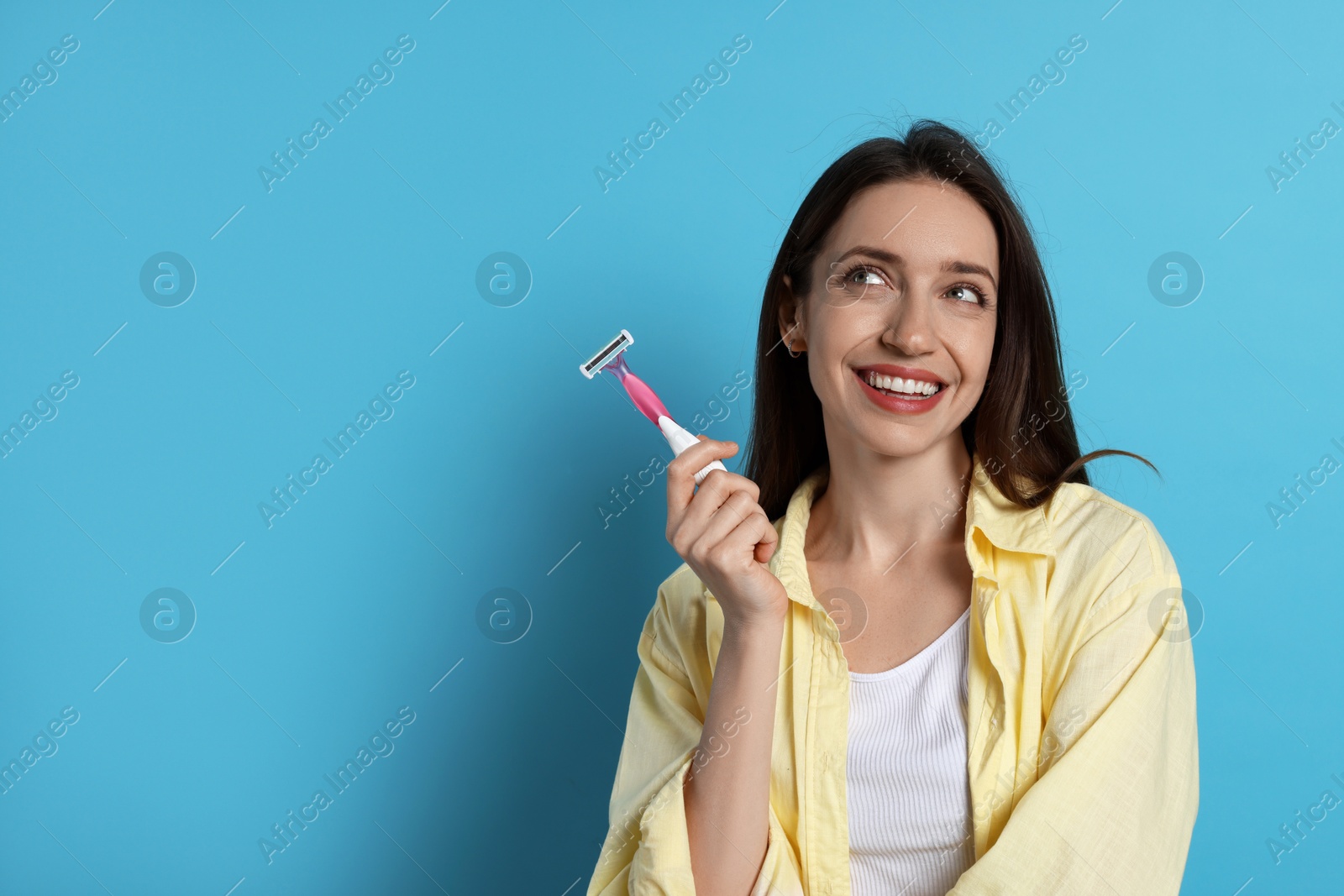 Photo of Happy woman with razor on light blue background, space for text. Hair removal tool