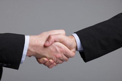 Photo of Businessmen shaking hands on grey background, closeup