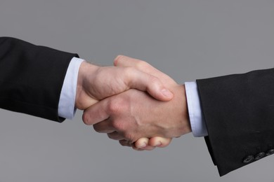 Photo of Businessmen shaking hands on grey background, closeup