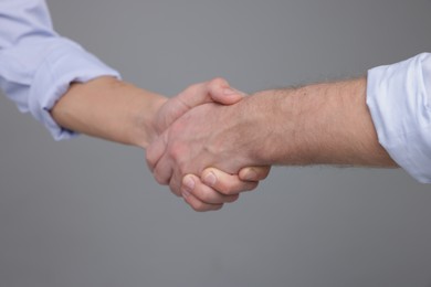 Photo of Businessmen shaking hands on grey background, closeup