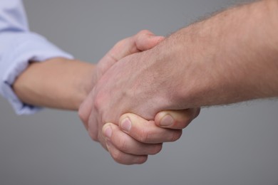 Photo of Businessmen shaking hands on grey background, closeup