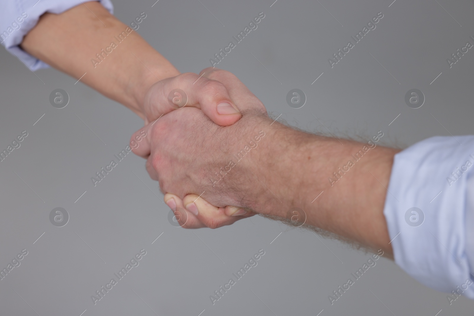 Photo of Businessmen shaking hands on grey background, closeup