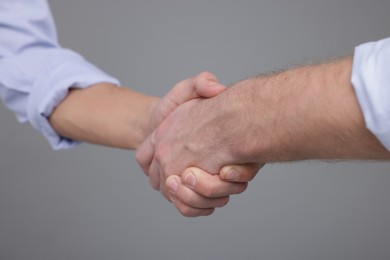 Photo of Businessmen shaking hands on grey background, closeup