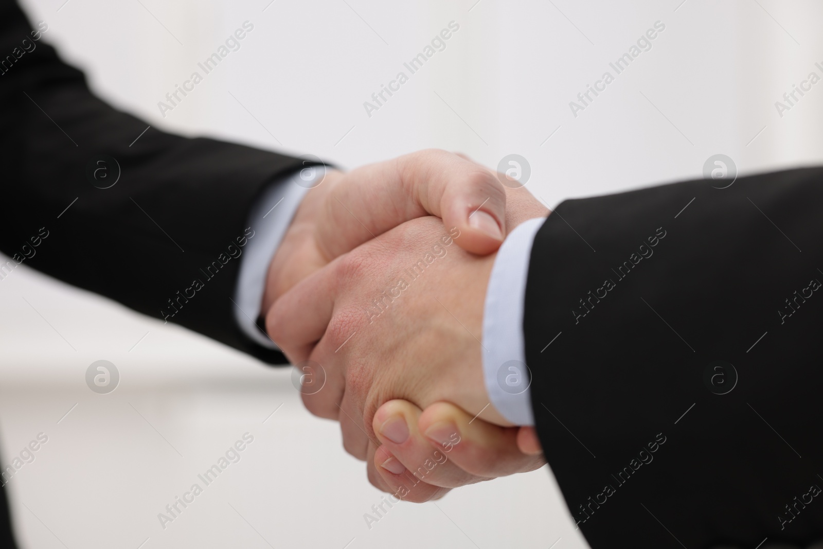 Photo of Businessmen shaking hands in agreement indoors, closeup