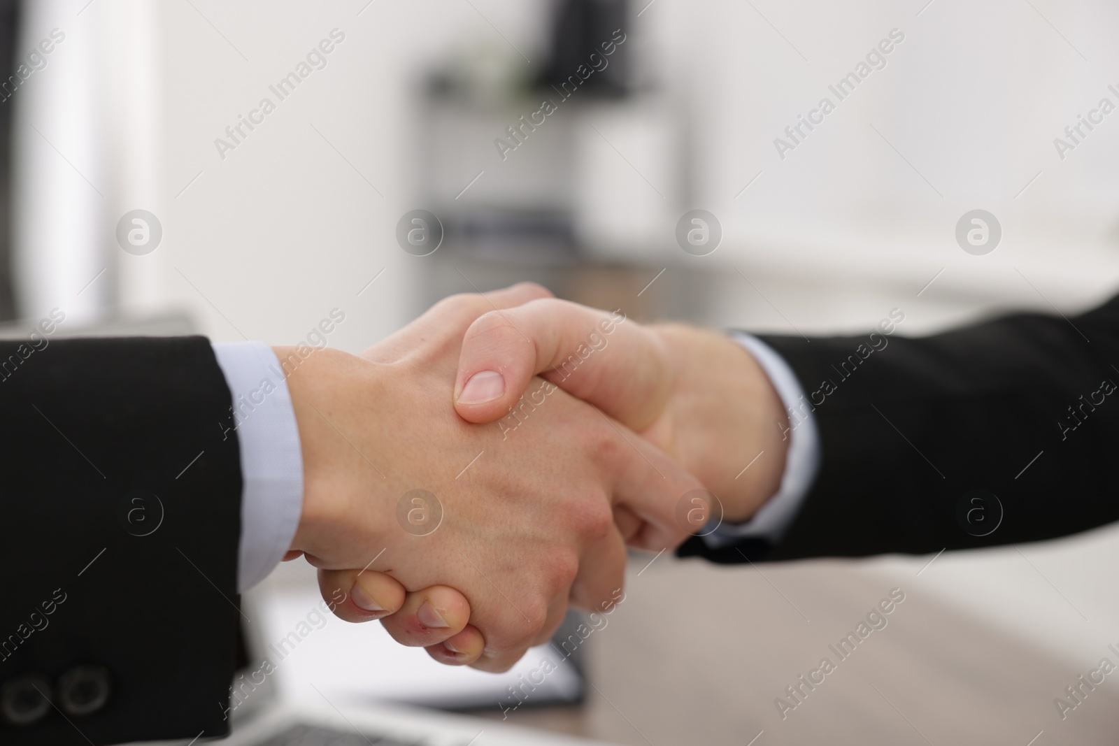 Photo of Businessmen shaking hands in agreement indoors, closeup