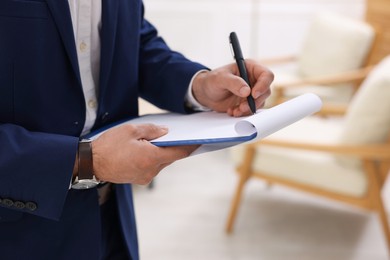 Photo of Real estate appraisal. Inspector with clipboard conducting property valuation at home, closeup