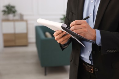 Photo of Real estate appraisal. Inspector with clipboard conducting property valuation at home, closeup. Space for text