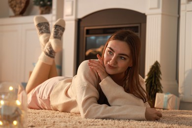 Woman in warm socks resting near fireplace at home