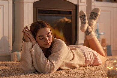 Woman in warm socks resting near fireplace at home